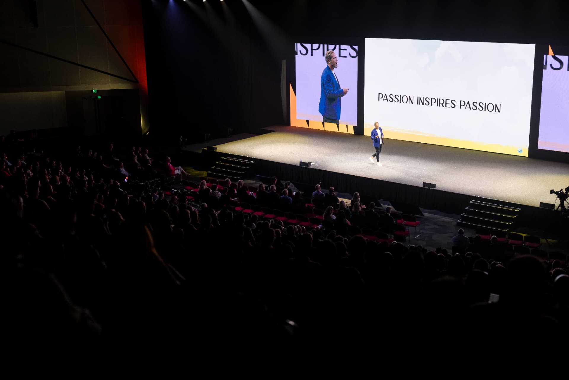 Seb Terry on stage at AMP Day with large screens displaying Passion Inspires Passion